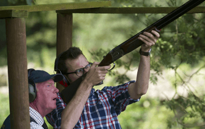 instructor teaching man how to aim in clay pigeon shooting